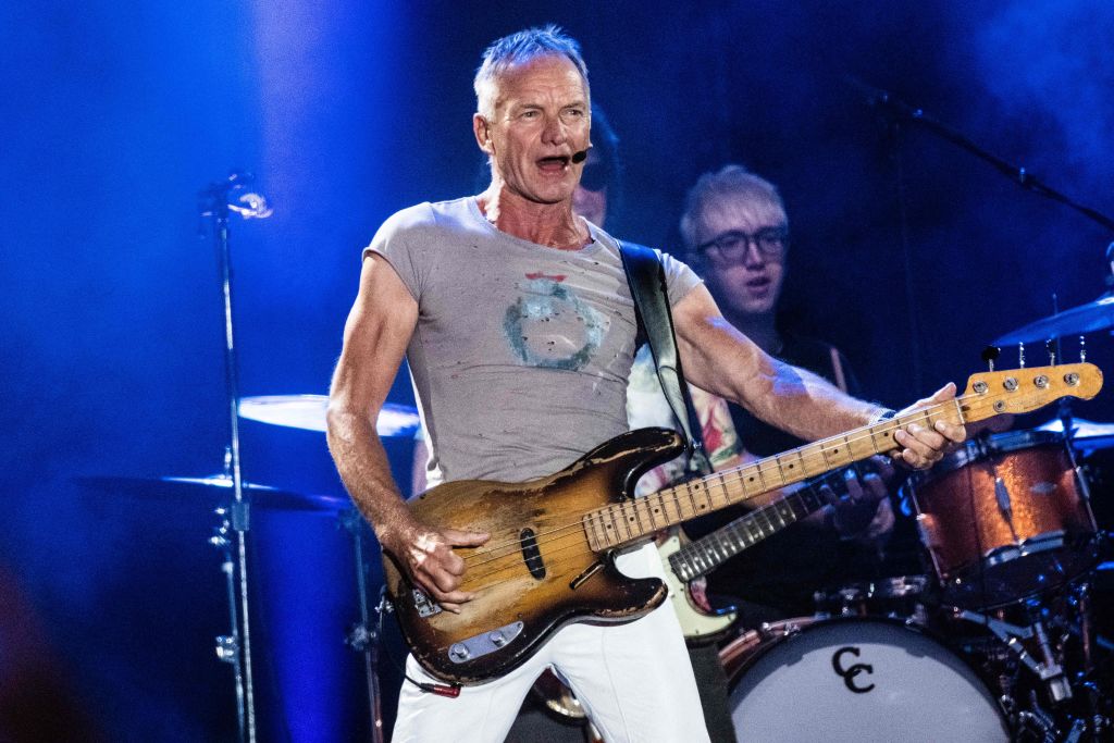 Sting singing with guitar on stage